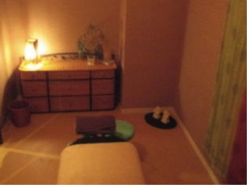 控えめな間接照明が置かれた落ち着いた印象の部屋である。中央には施術を受けられるベッドが置かれている。