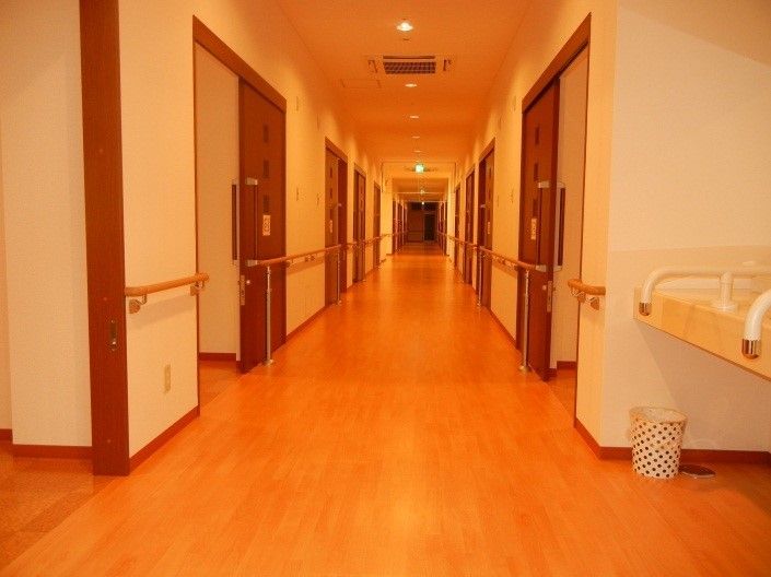 通路の両側に手すりを設置し、入居者様が安全に居室までご移動いただけるよう配慮している。居室の扉は開きやすいスライド式である。