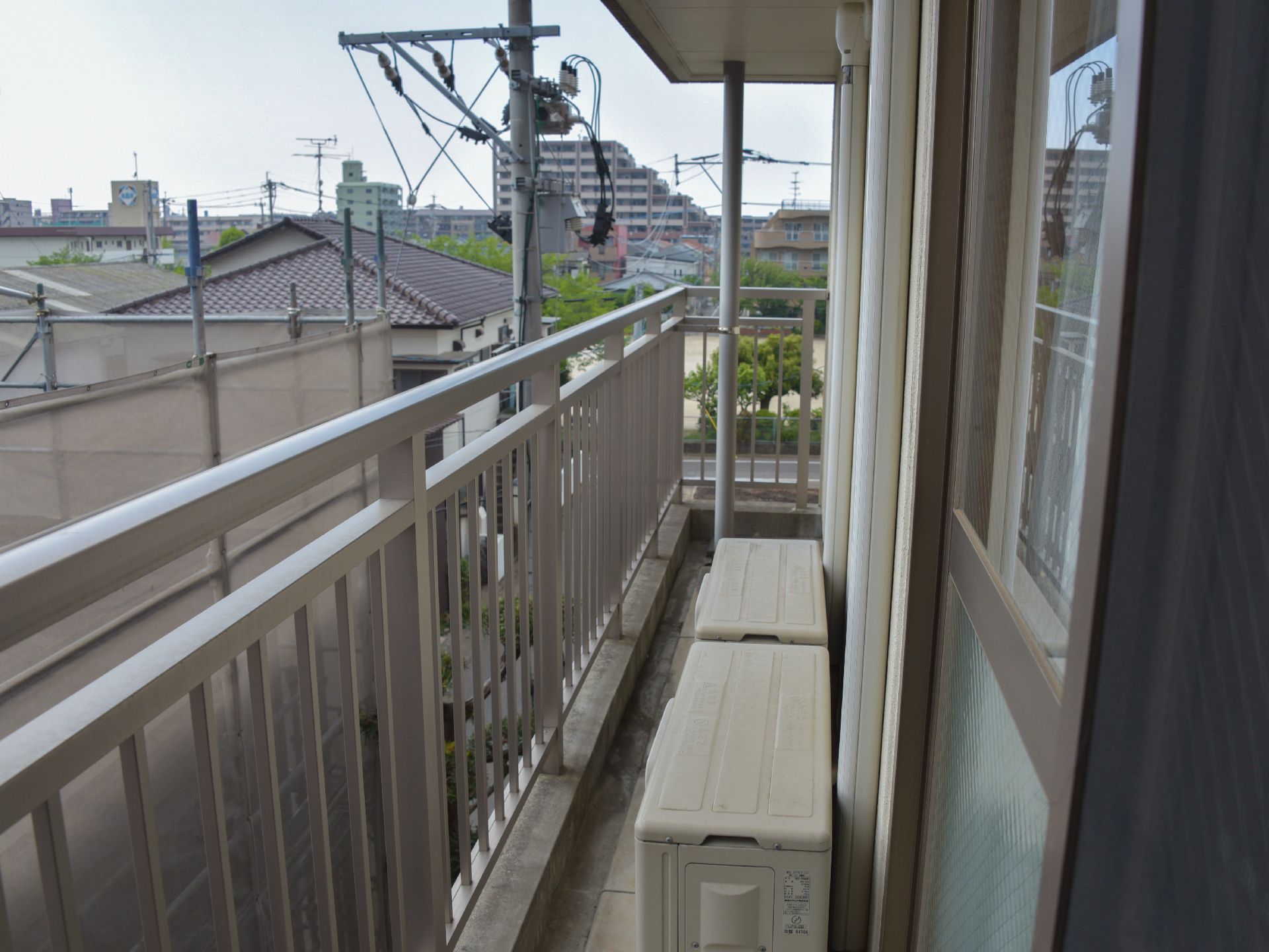 居室の外には小さなベランダが用意されている。野外には安全のために柵があり、エアコンの室外機が置かれている。