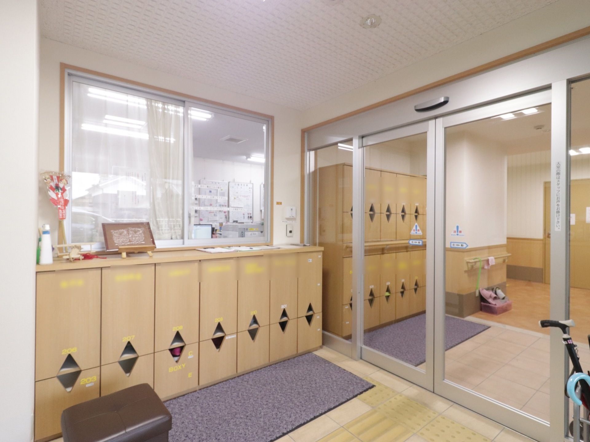 入ってすぐ左に受付がある。扉は自動ドアで床には絨毯が敷いてある。入居者様の名前が書かれた下駄箱がある。