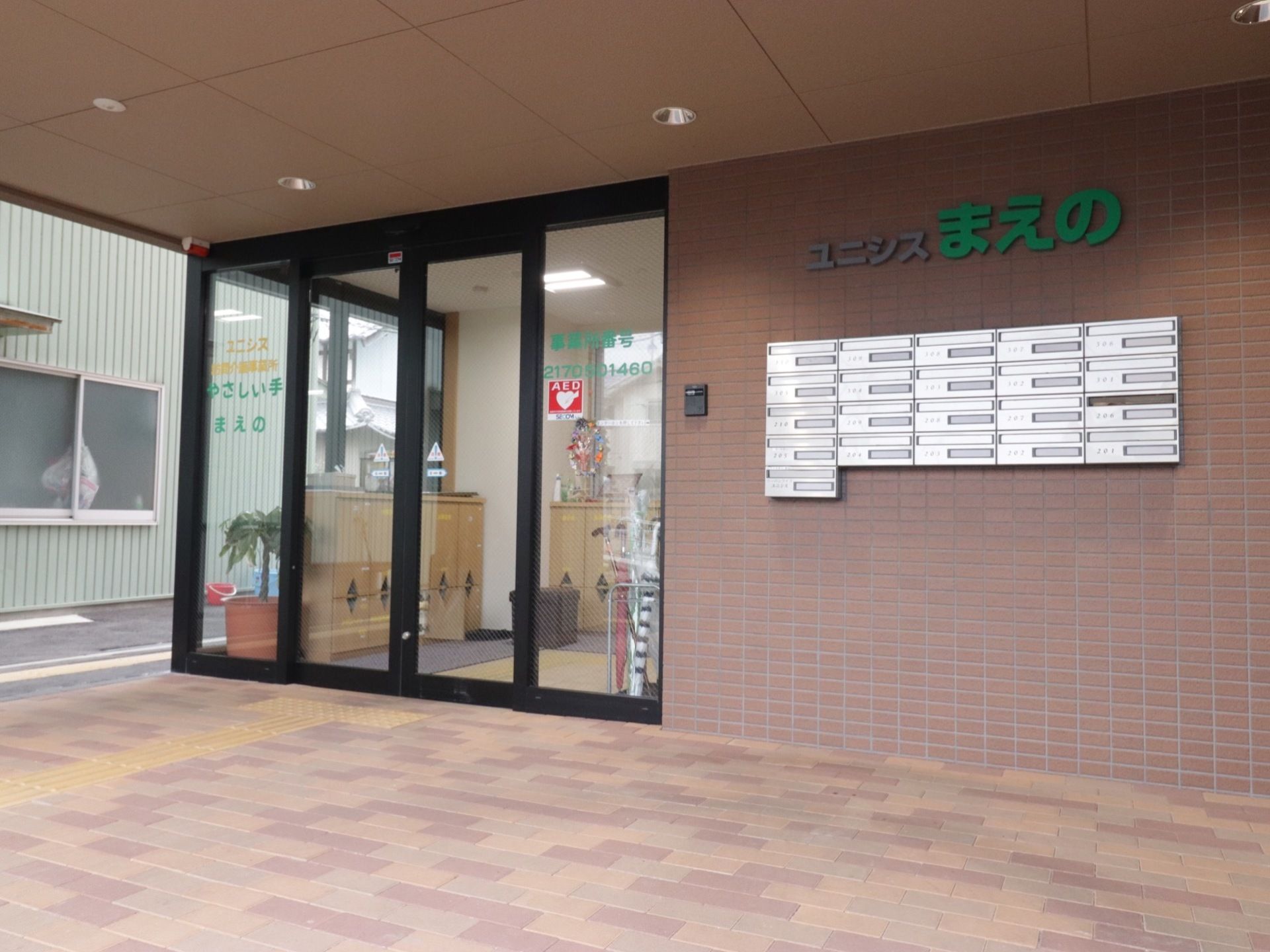 施設入口の様子。透明な自動ドアで、中の様子が見える。外から中までバリアフリー設計になっており、床に点字ブロックが続いている。