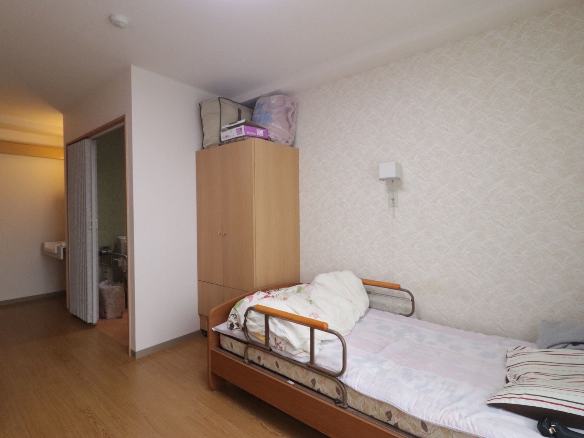 両側に柵のあるベッドがある。その奥には洗面台トイレがある。クローゼットがある。その上には予備の布団が置いてある。
