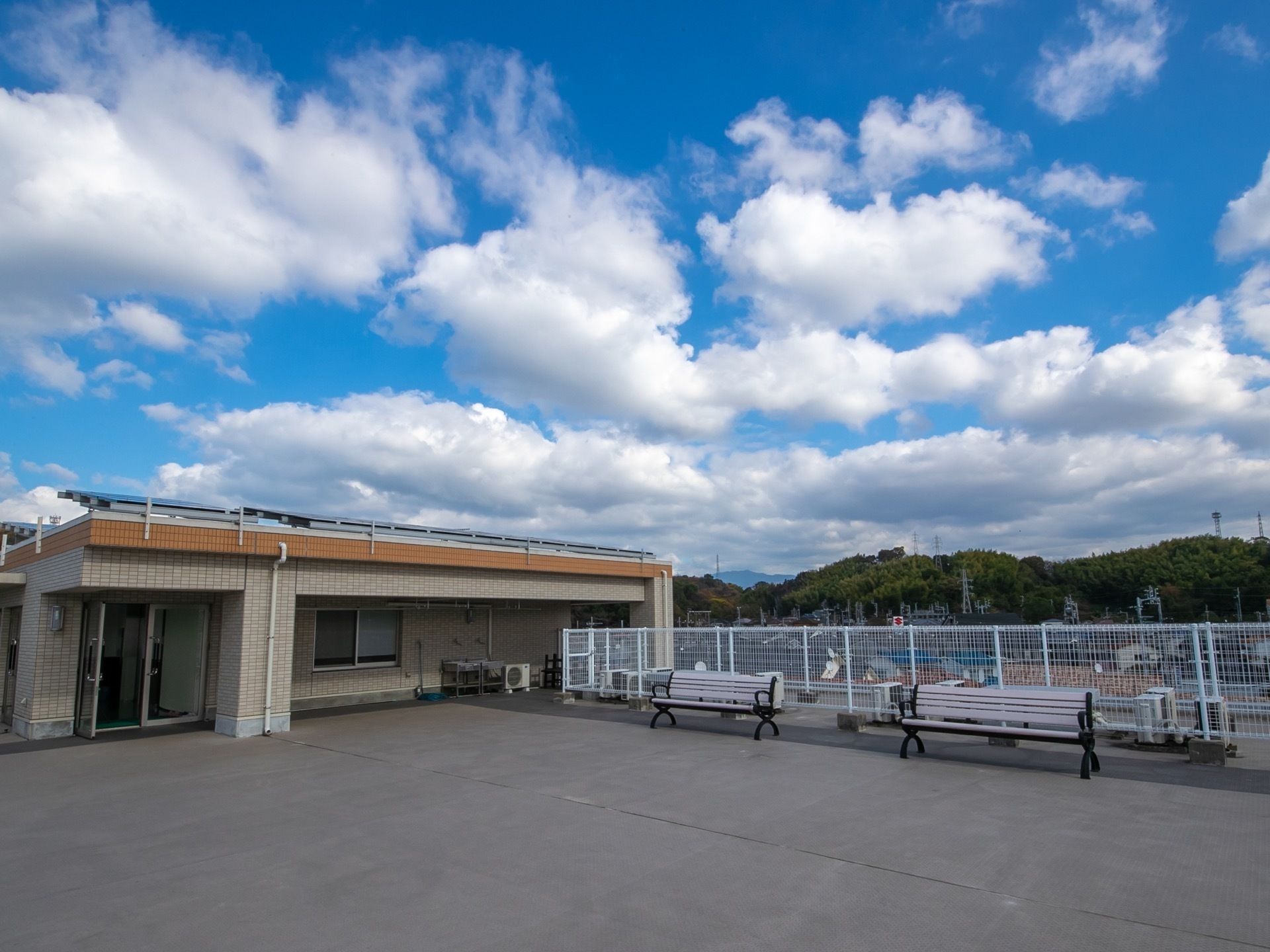 広く開放感のある屋上である。白いフェンスがめぐらされ、白いベンチが置かれている。出入り口付近には水道が設置されている。