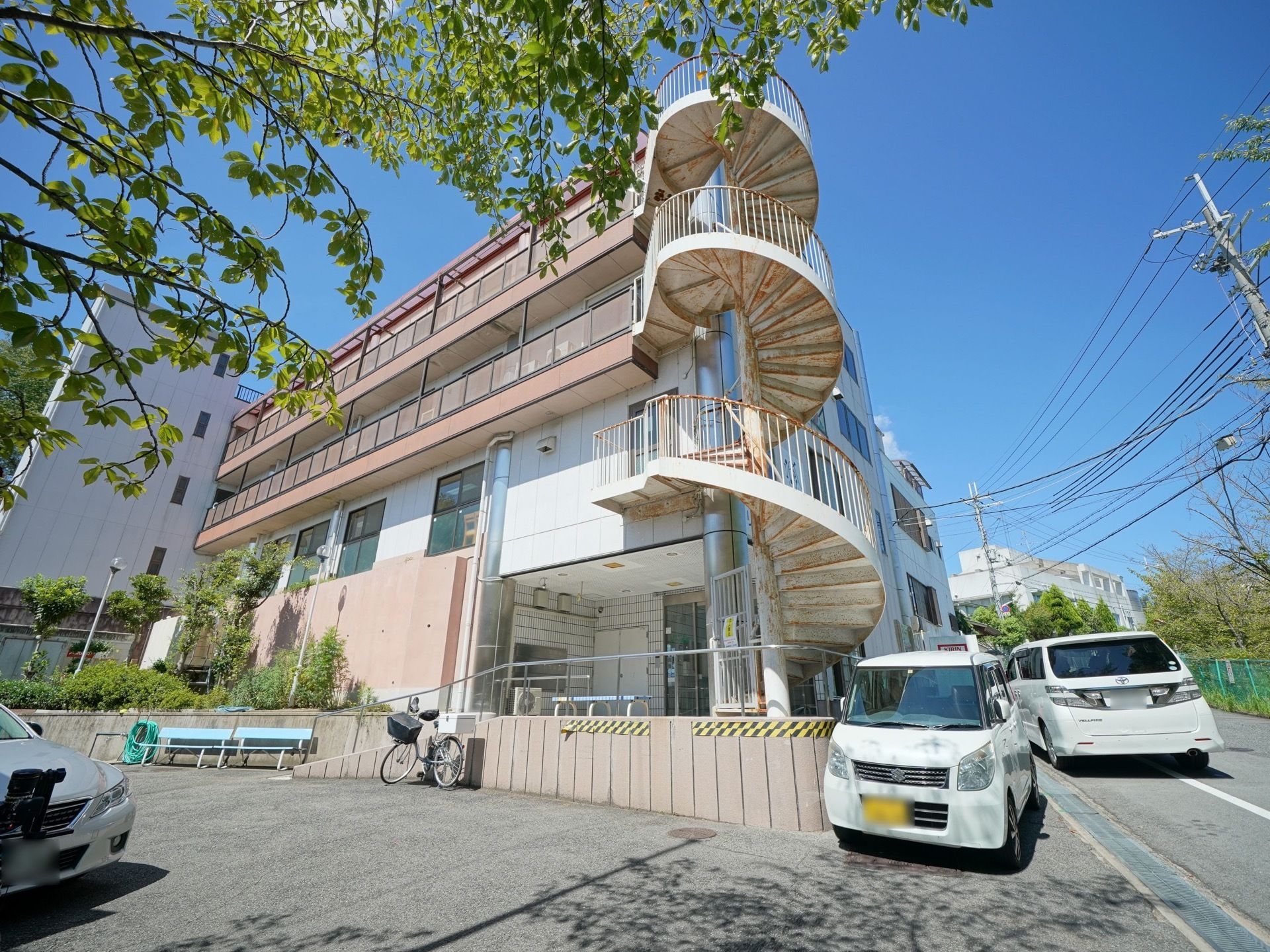 施設のすぐ脇に広い駐車スペースがある。玄関から駐車場へはスロープが設置されている。駐車場には自転車も停まっている。