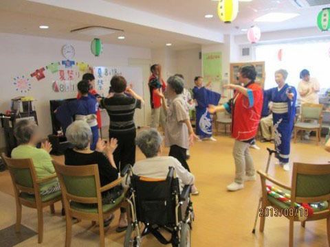 職員の方たちと一緒に室内で輪になり盆踊りを楽しむご入居様方