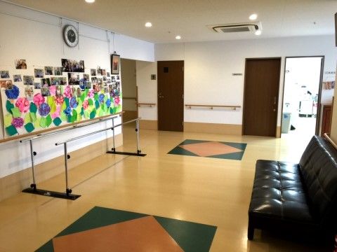 折り紙で作った紫陽花とご入居様のお写真が飾られた壁の近くにある歩行訓練バー