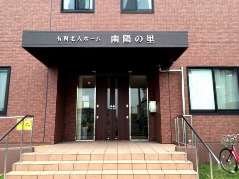 オレンジの階段を上った先の、茶色い外壁の老人ホームのエントランス