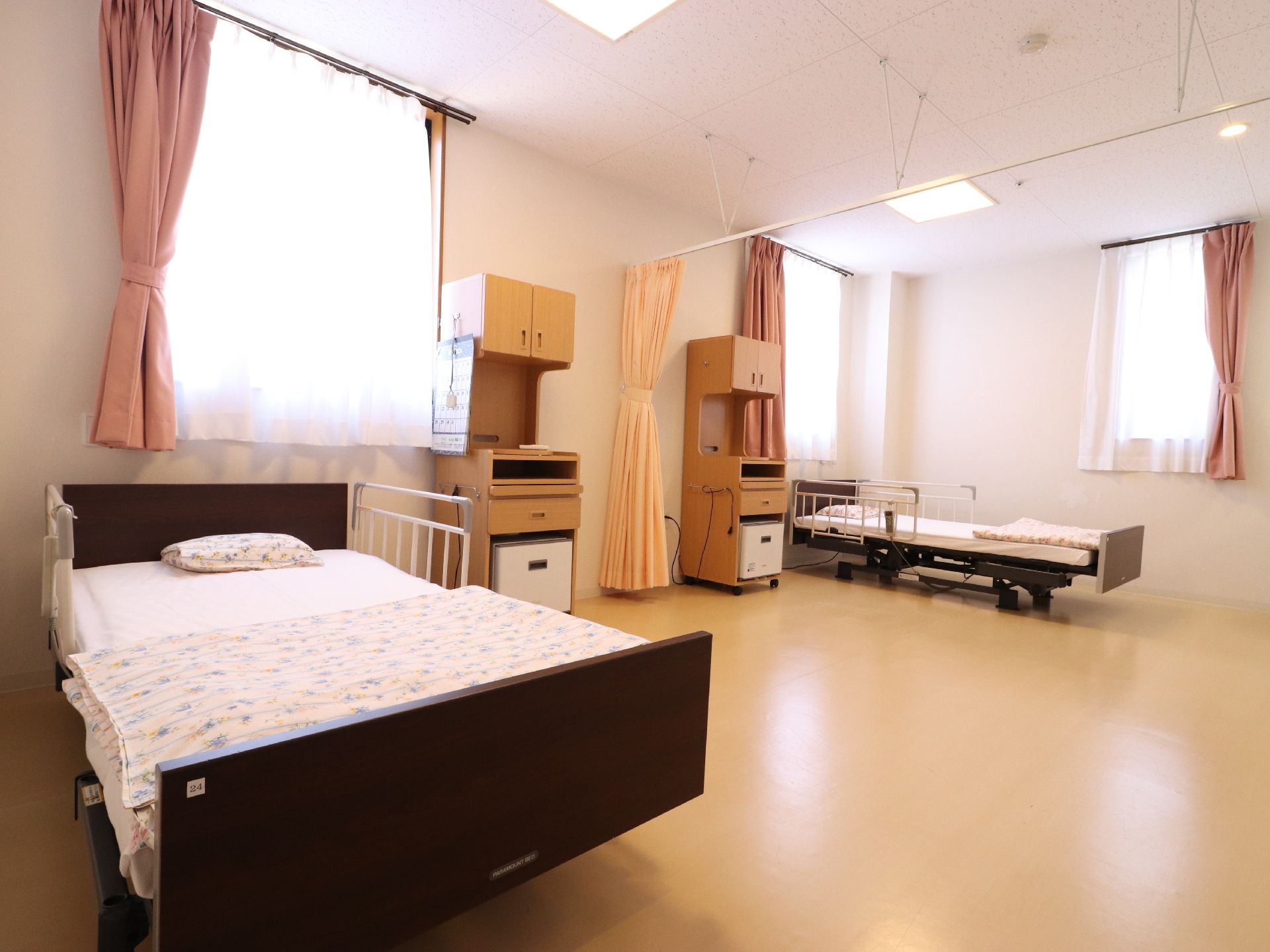 2人が過ごすことができる相部屋になっていて、カーテンで仕切られている。電動介護ベッドや棚机が用意されている。