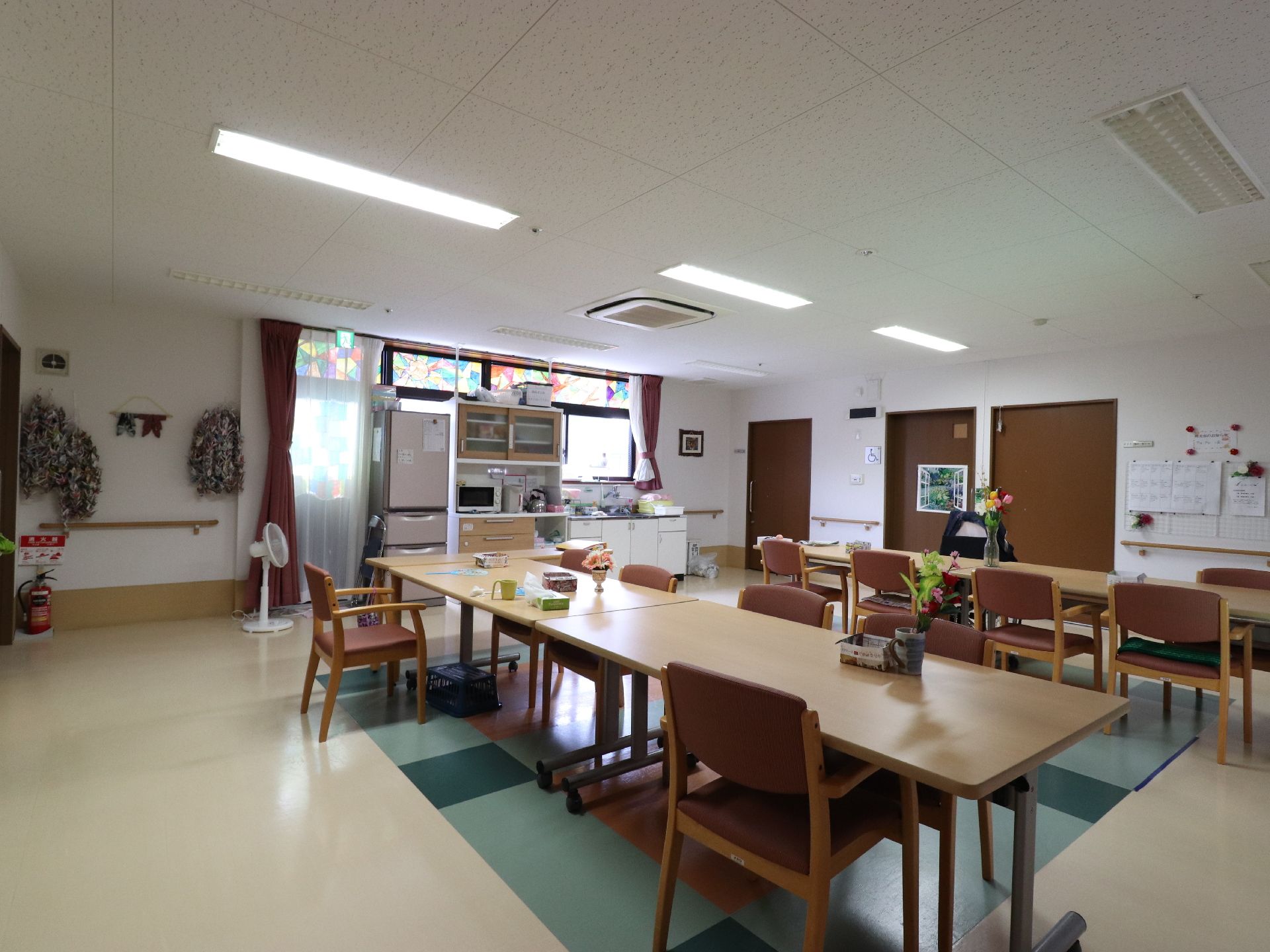 食堂・共有スペースには、キッチンカウンターや冷蔵庫、食器棚、電子レンジが置かれている。窓はステンドグラス調になっている。