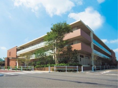 周囲に緑が植えられ、オレンジの外壁で3階建ての建物