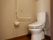 居室のトイレは洋式である。壁にはＬ字型の白い手すりが取り付けられている。その近くには緊急呼び出しボタンがついている。