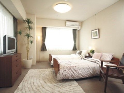 ベッド2台とテレビや観葉植物を配置した洋室