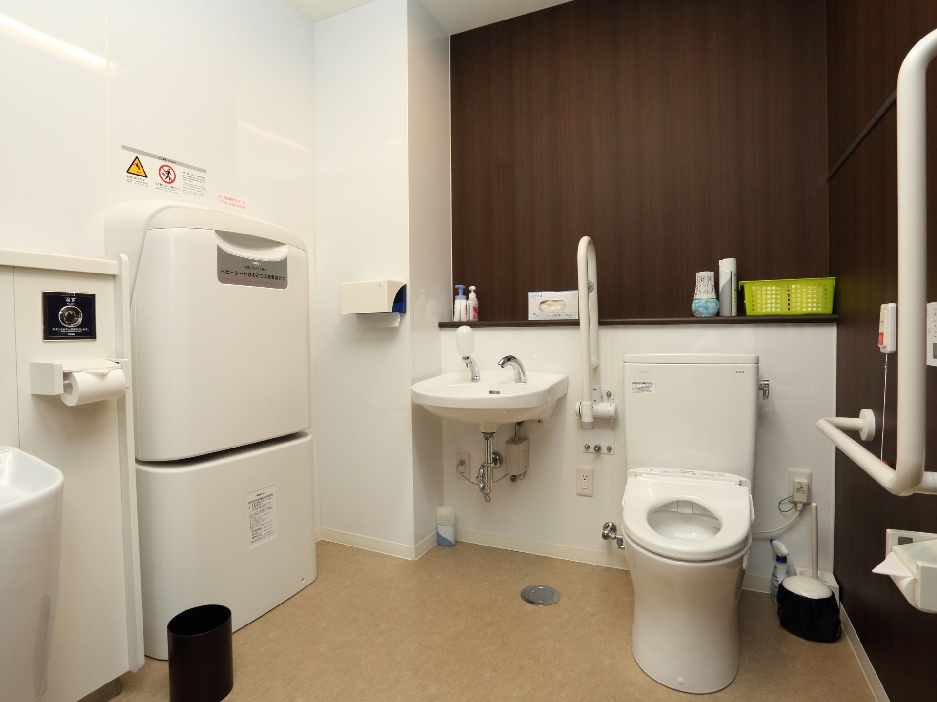 広々としたトイレスペースには、便器横にシンプルな洗面台を設置している。横側の壁におむつ交換台を備えている。