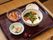 てんぷらやゆで卵、わかめやニンジンなどの具だくさんのうどんがメインのメニューである。それに２品の小鉢とデザートが添えられている。