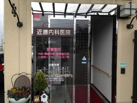 診療案内がガラスドアに印字された内科医院の入り口自動ドア