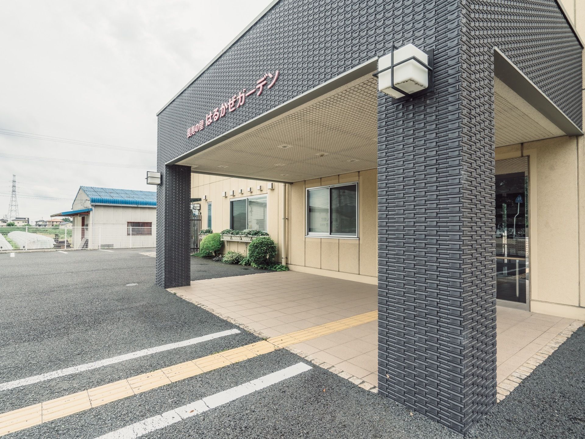 シックなカラーが施された施設外観である。外壁には施設名が記された看板が設置されており、通路から目立ちやすい。