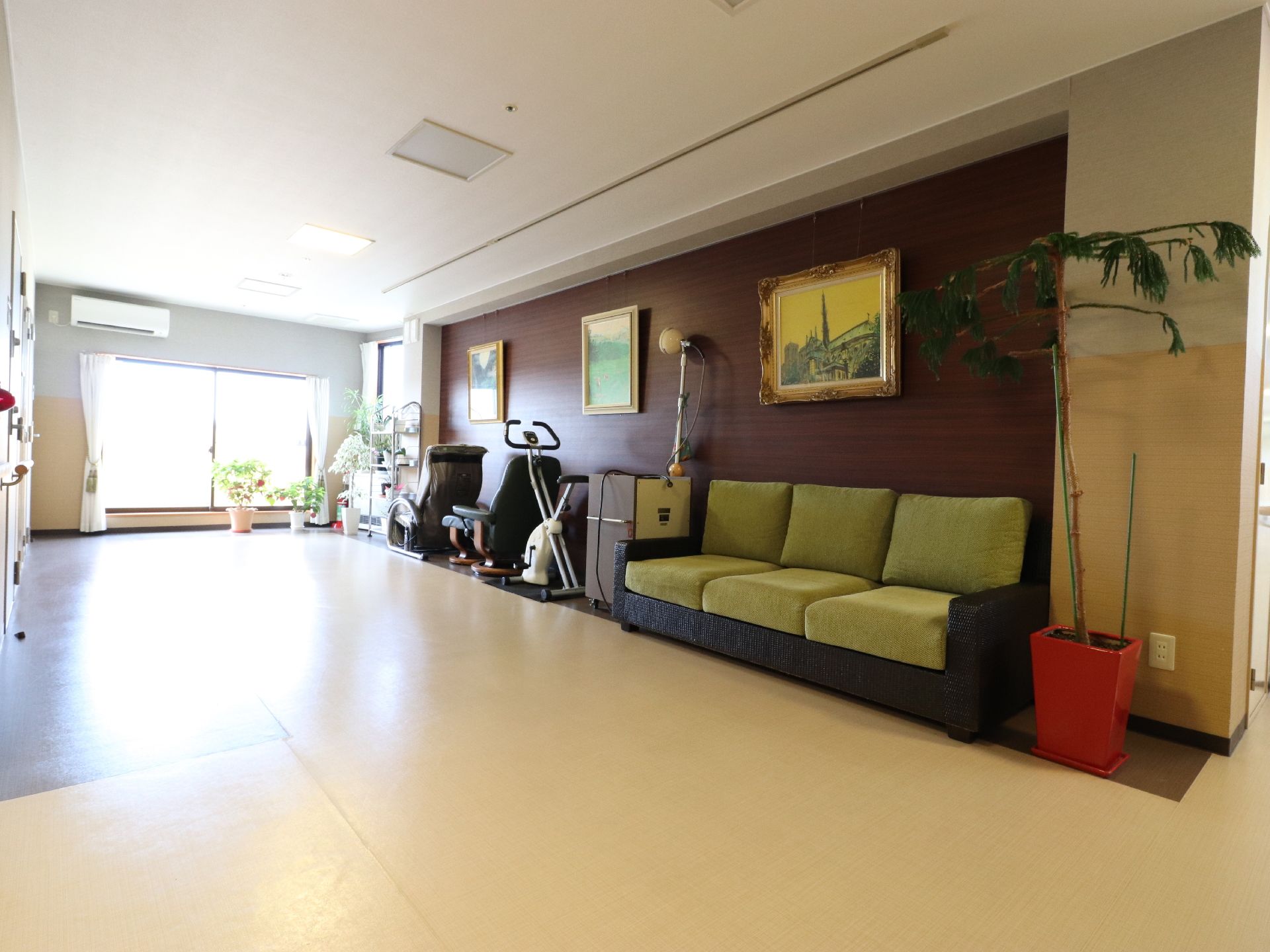 廊下にある広々とした空間には、3人掛けの大きなソファーやマッサージ機が置かれている。壁には、絵がかけられている。