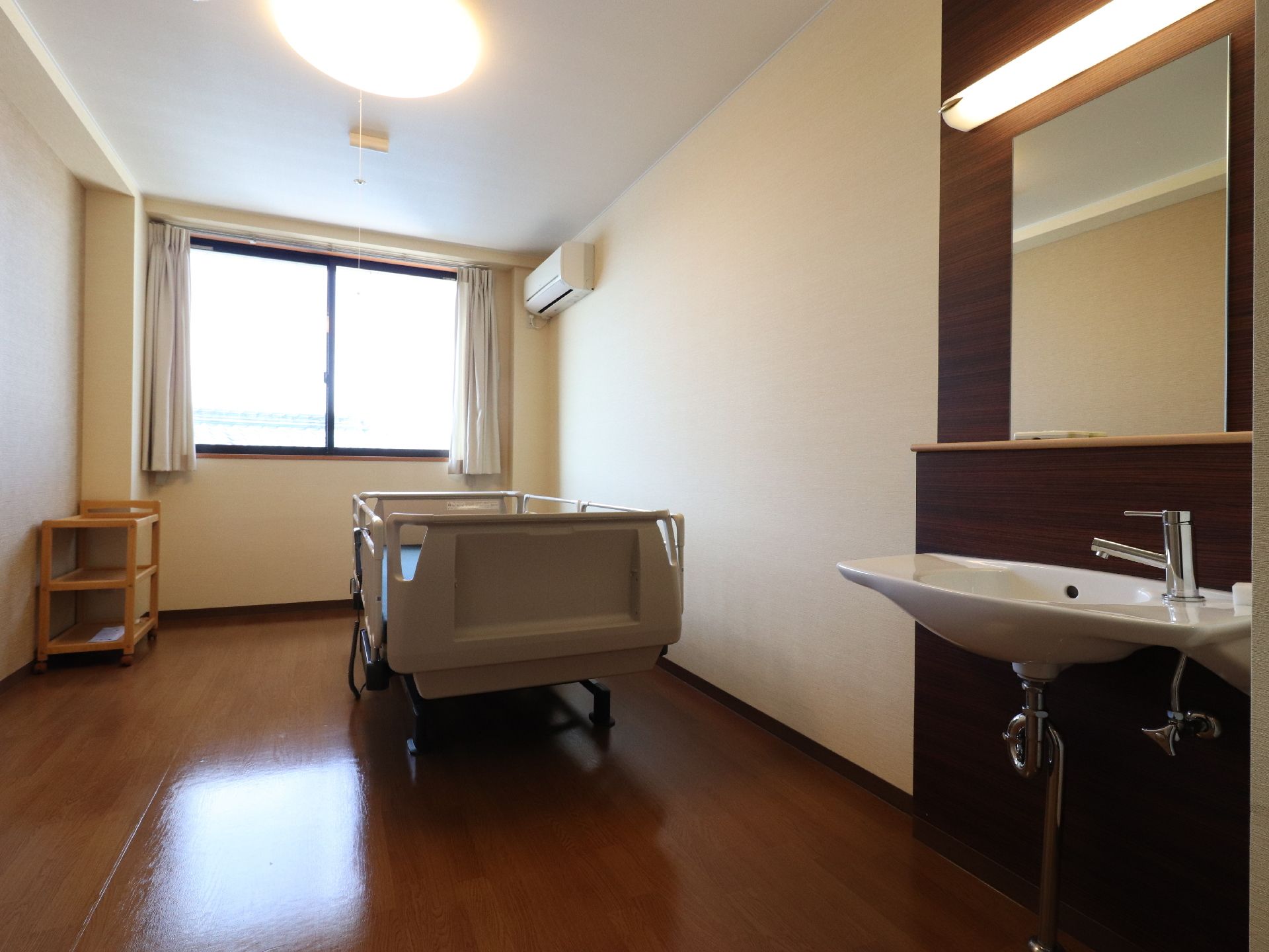 床が磨かれピカピカに光った個室にある洗面所付近には、鏡や照明がついており、コップ等を置くことができる小さい棚がついている。