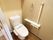 手すり、タオル掛けのついた、白い便器があるトイレの個室。用を足した後ですぐに手を洗い、拭くことができる。