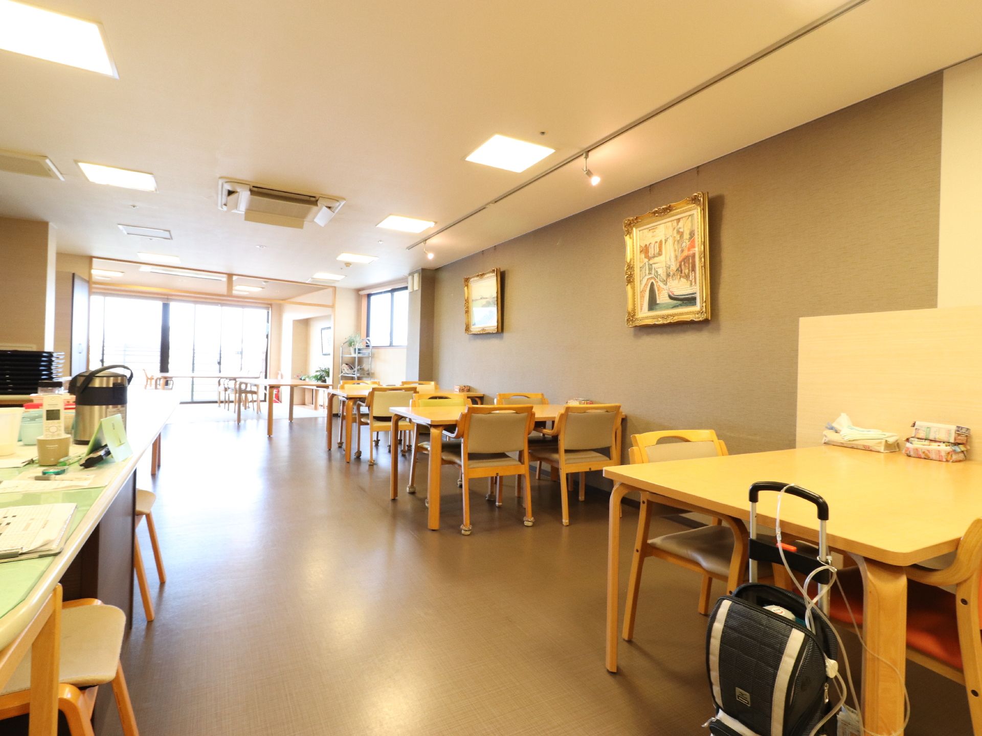 左手にカウンターがあり、椅子が並べてある。右手から窓にかけて、テーブルが五台並べてある。ティッシュボックスなどがテーブルに乗っている。