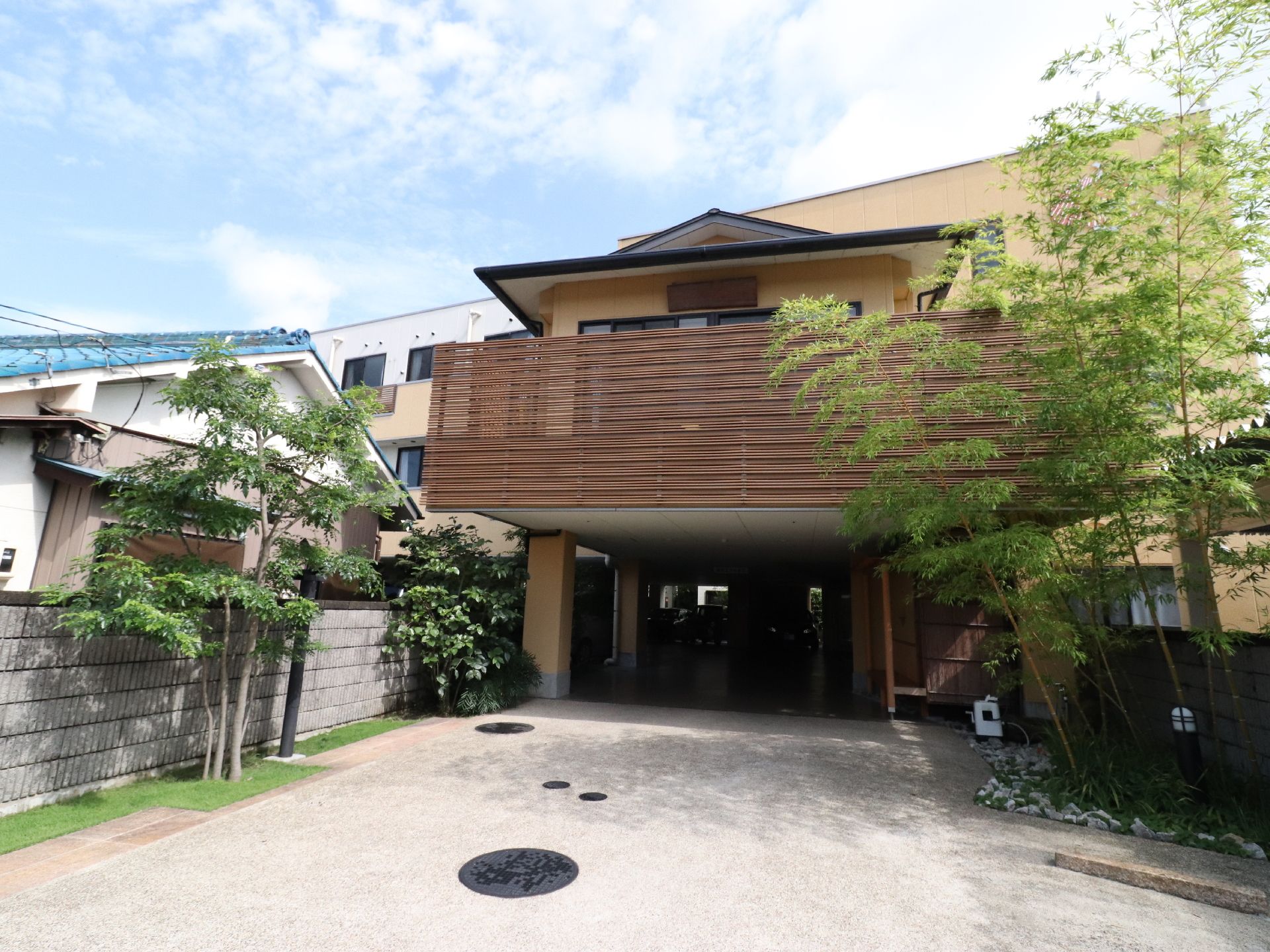 施設の一階は駐車場になっていて、奥に数台車が停まっている。コンクリートで整備されている。駐車場入口には庭があり、植栽も綺麗。