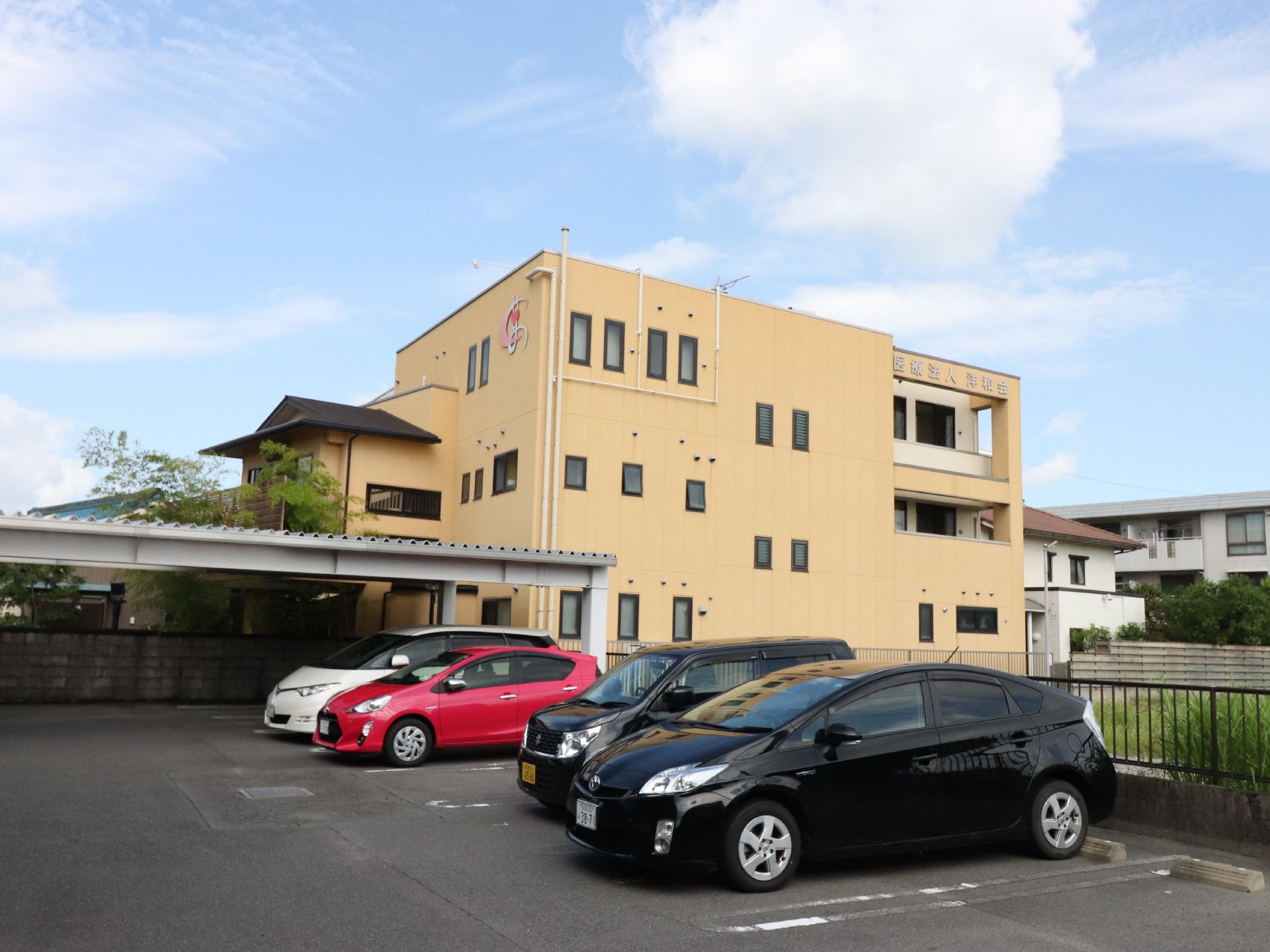 駐車場から見えているのは、施設のマークがついている玄関側と玄関から見て右のサイドである。薄い黄色に塗られた外壁がある。