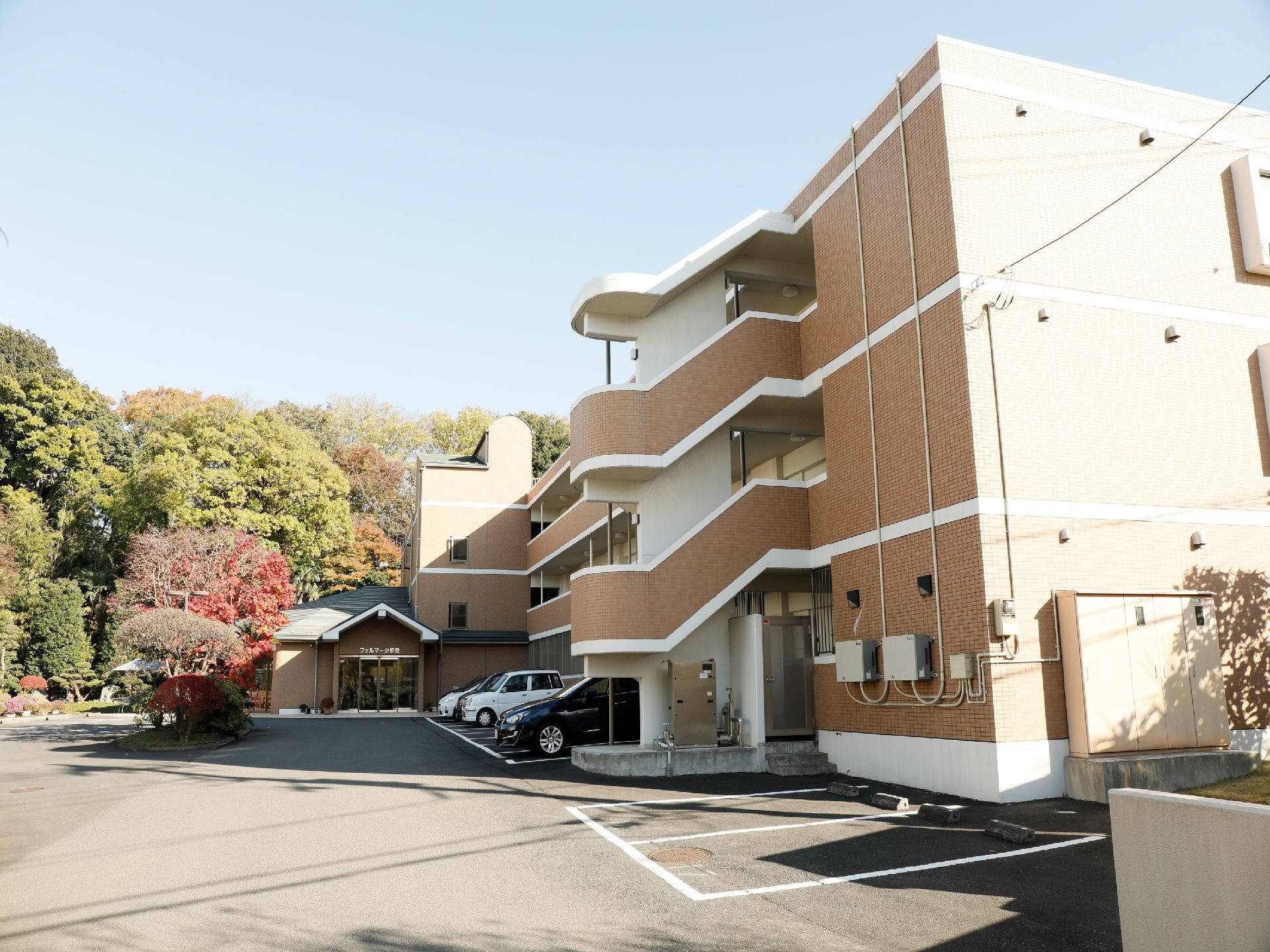 ３階建てのマンションのような大きな建物である。敷地内には専用の駐車場が沢山ある。施設の庭先には、大きな樹木が茂っている。