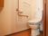 トイレはフローリングで、壁にはくの字型をした手すりを設置している。便座には温水洗浄機能がついている。