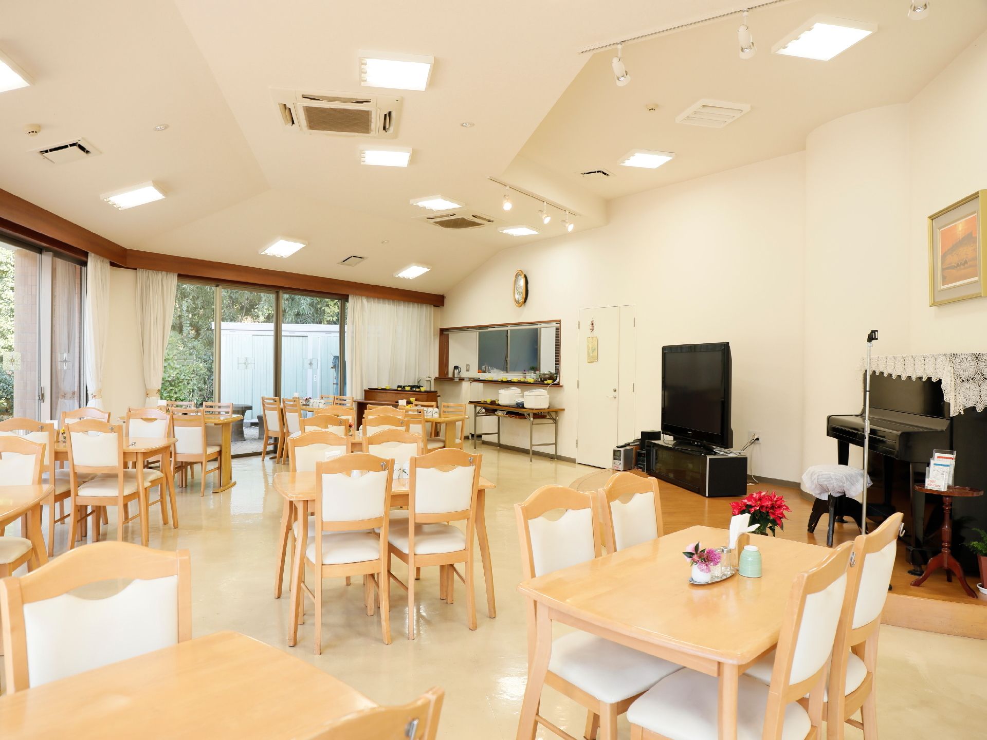 食堂には、机が窓に沿って並んでいる。キッチンカウンターがあり、その前には炊飯器をセットしている。テレビとピアノを共有している。