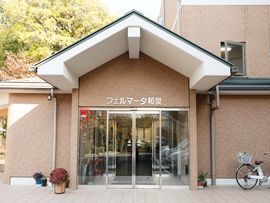ライトブラウンの建物に入る際に利用するガラス扉のエントランス