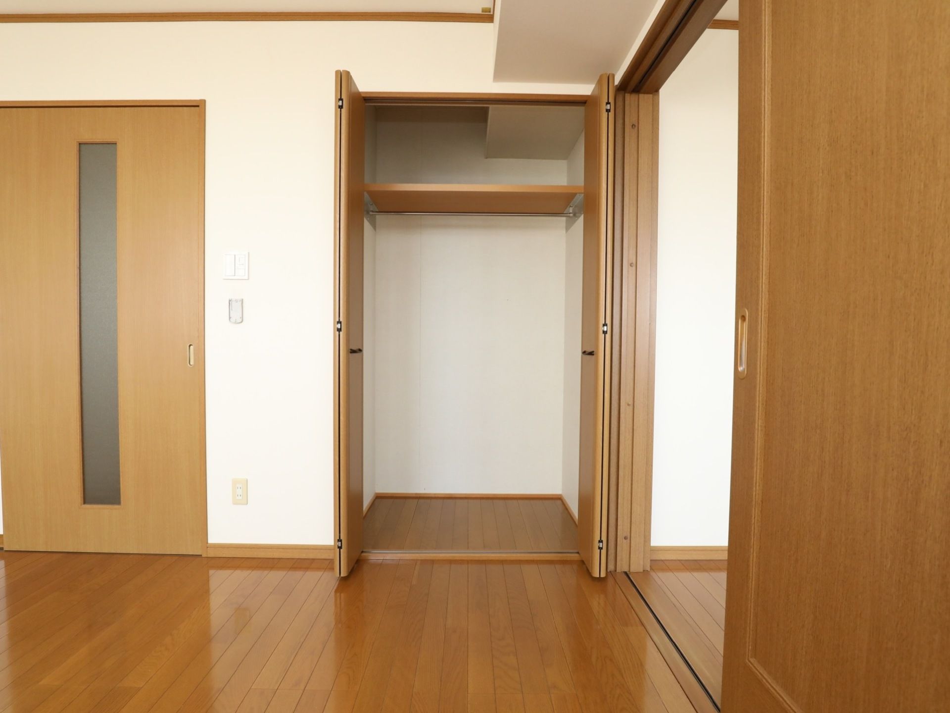 床とドアが木で明るく落ち着いた雰囲気の居室である。広いウォークインクローゼットも備えられており、ドアは引き戸である。