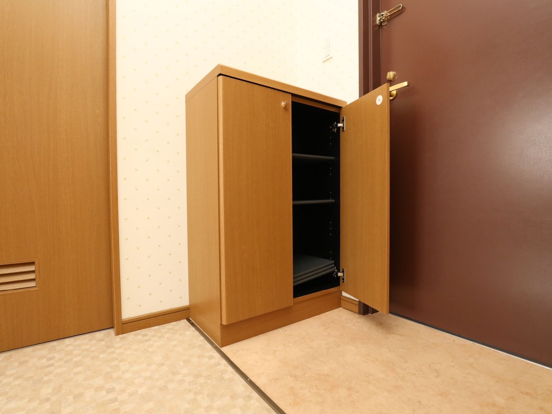 居室の入り口には段差がなく、靴がたくさん収納できる靴箱も備えられている。壁の白、ドアや靴箱の茶色と明るく落ち着いた空間である。