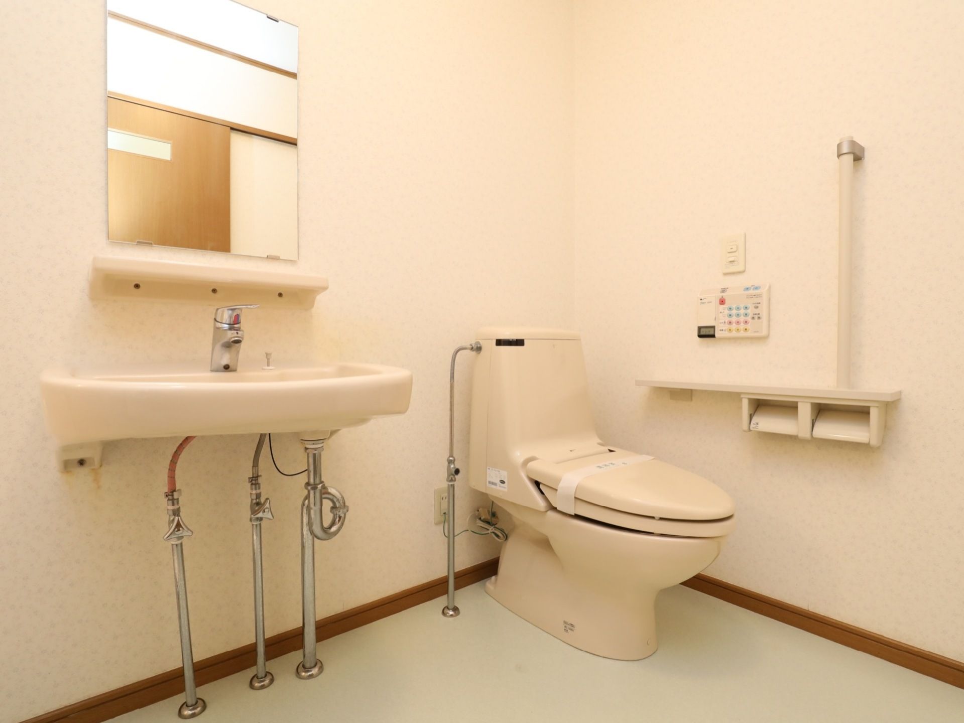 アイボリーで統一されたトイレは広く、洗面も備えられている。トイレの横には手すりが設置され、安全にも配慮されている。