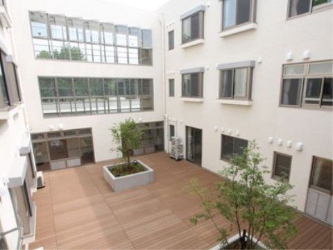 白い建物で囲まれ、所々に木が植えられた吹き抜けの中庭