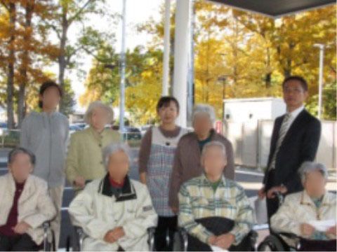 玄関外に整列し、後ろに並ぶ職員と前に並ぶ車椅子の入居者
