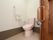居室内のトイレは広々としたスペースが確保されており、奥の壁には手すりやトイレットペーパー掛けが設置されている。