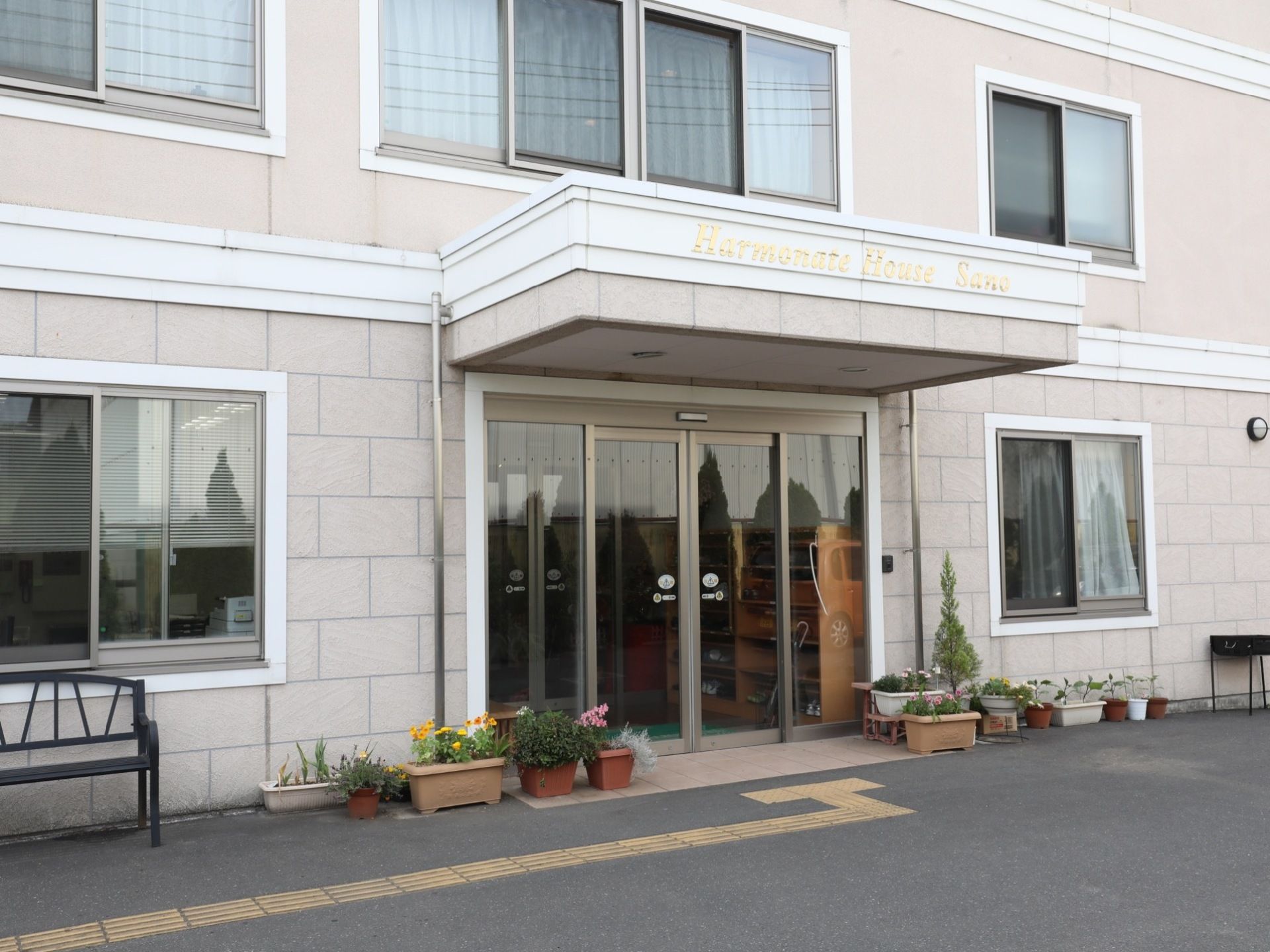 施設正面玄関の様子。自動ドアの上に張り出したひさしの前面には、デザイン的な側面の強いロゴが取り付けられている。