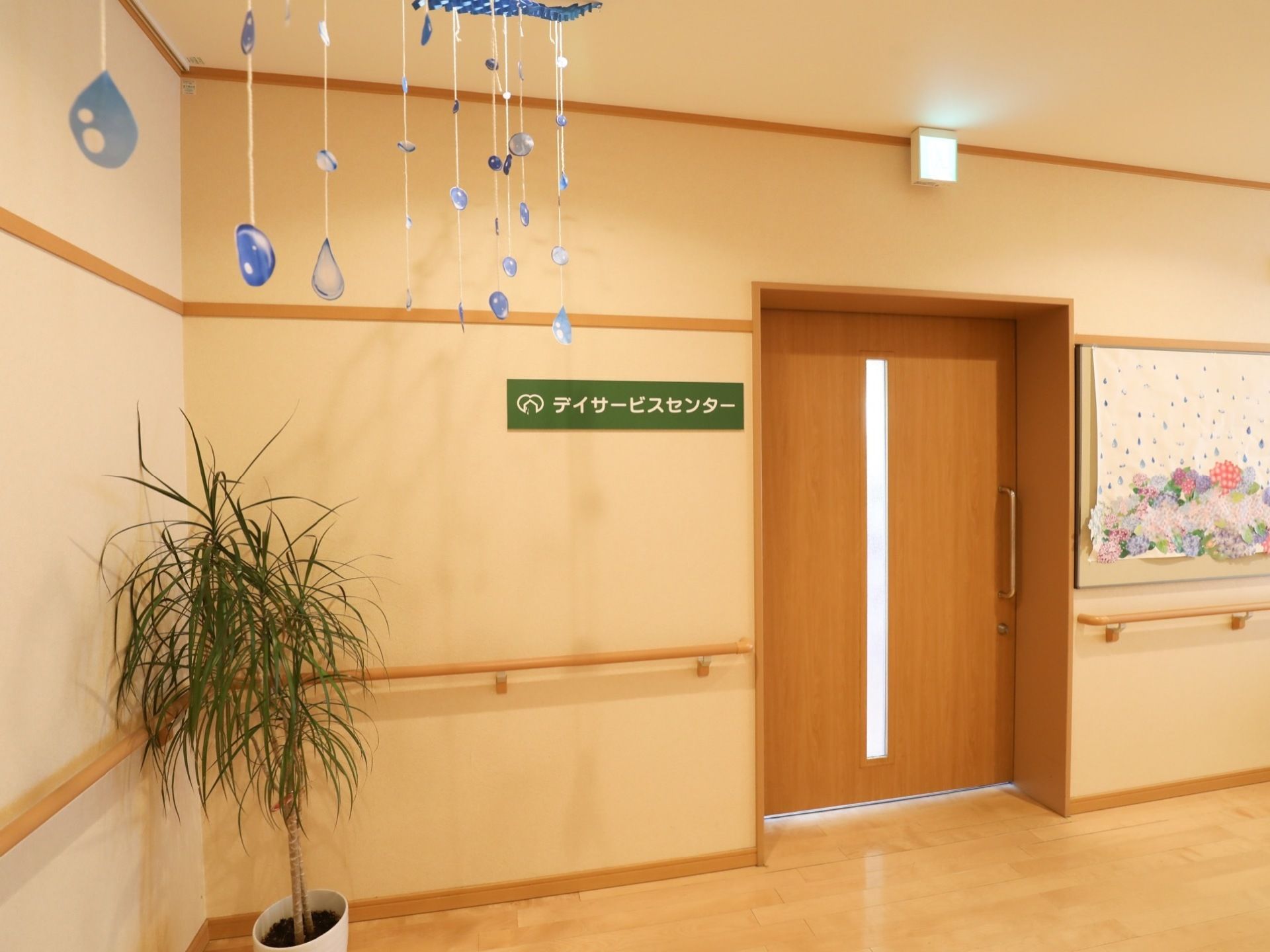 施設内にはデイサービスセンターも併設されている。ドアの横には緑色のプレートがあり、上には誘導灯が取り付けられている。