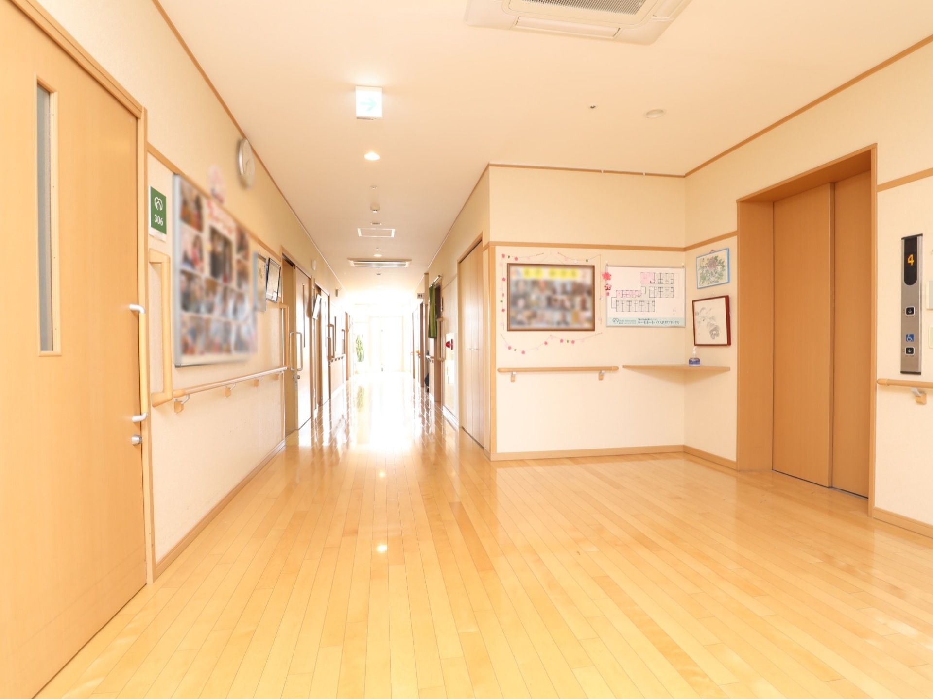 施設の廊下の様子。床全体は明るい色のフローリング敷きになっており、壁にはそれとほぼ同じ色の手すりが設置されている。