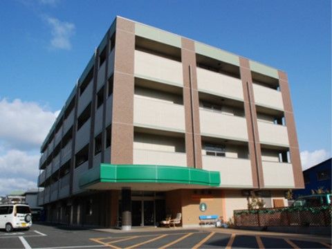 グリーンのエントランスがアクセントになった広い駐車場のある建物