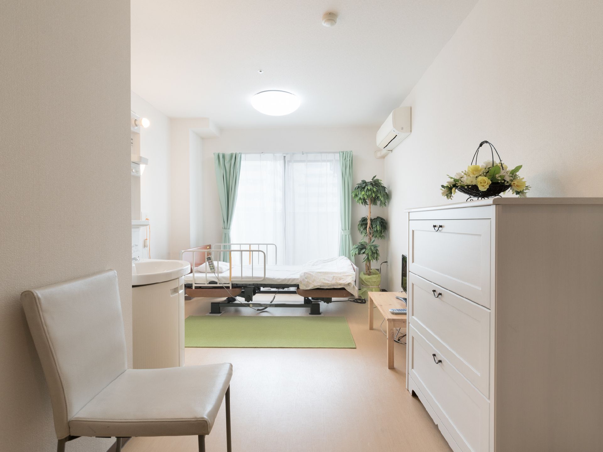 部屋は、壁、家具、洗面台が白で統一されている。また床も白みがかった色をしている。そしてカーテンはグリーンである。