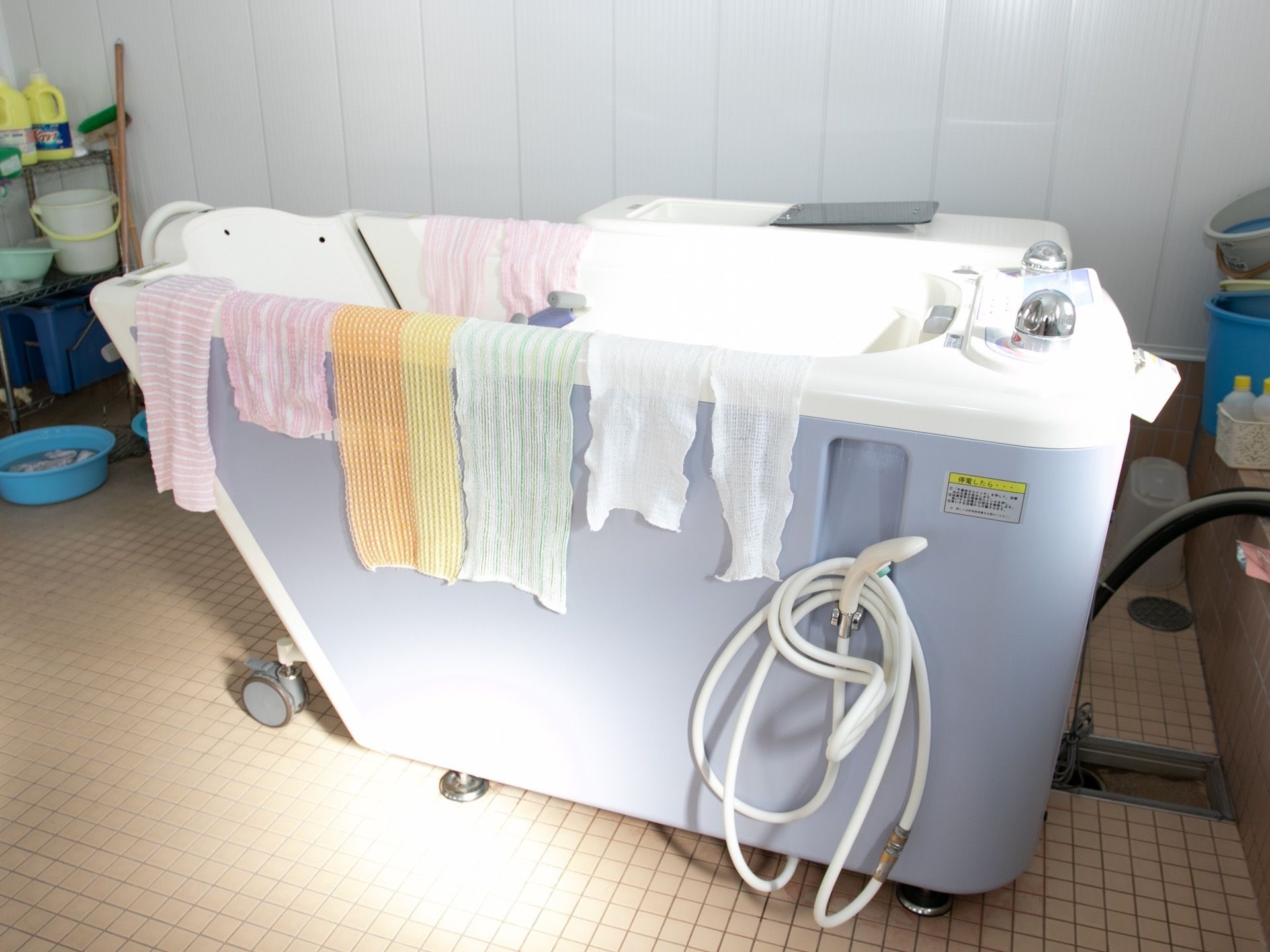 大浴場に介護浴槽があり、まわりに体を洗うタオルなどが掛けられている。シャワー設備と搬送車が備わっている。