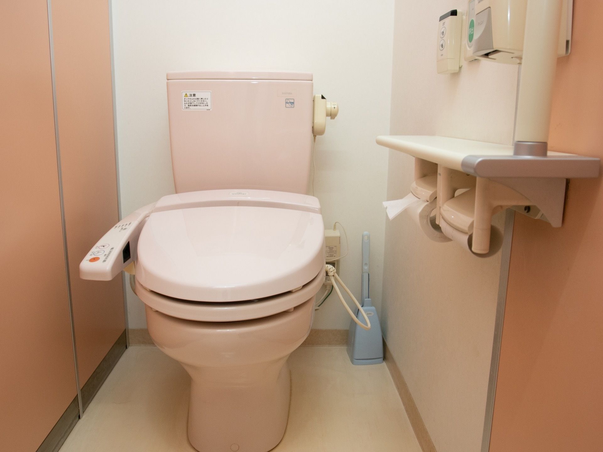 温水洗浄便座付きの便器が設置されたトイレである。ペーパーホルダーが２つ取り付けられ、手すりも備え付けられている。