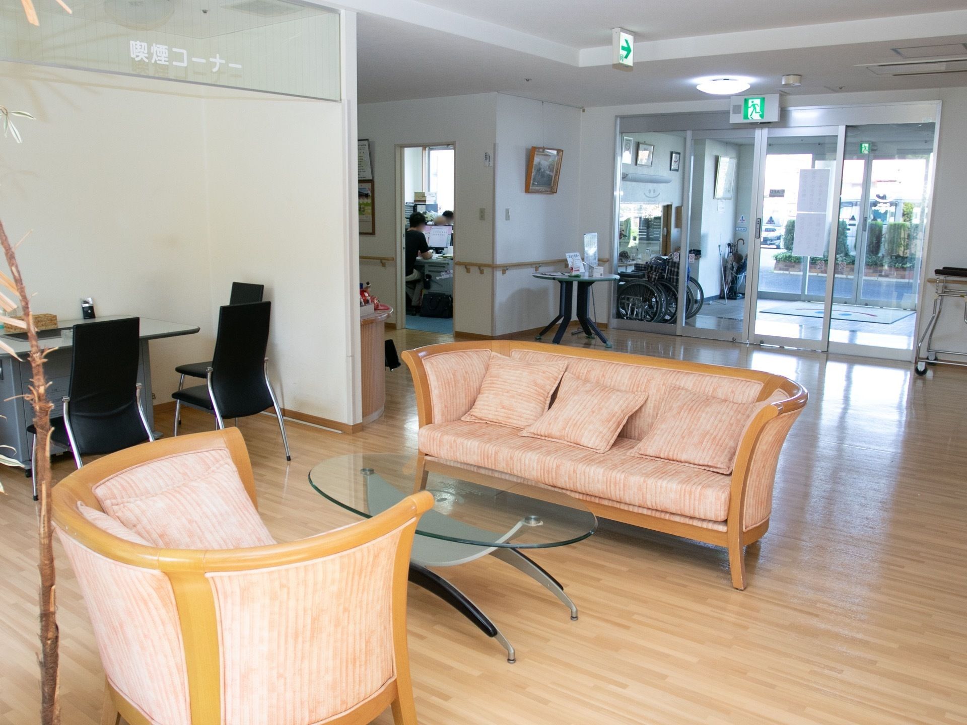 玄関から入ってすぐのロビーである。温かみのあるフローリングの床で、ソファやテーブルがある。隣には、喫煙コーナーも設けられている。