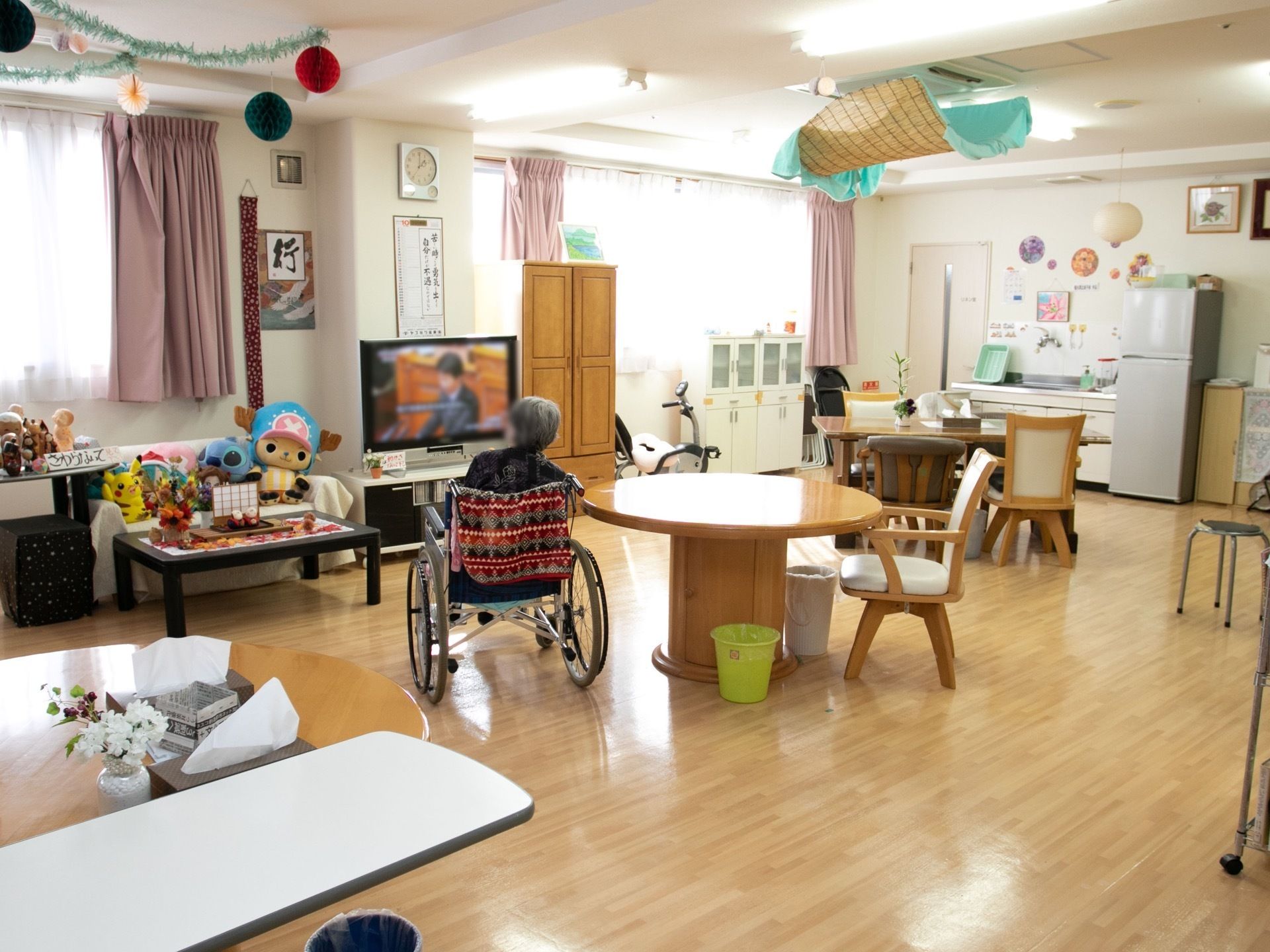 ゆったりと奥行きのある食堂である。テーブルと椅子が置かれ、テレビも設置されている。流し台や冷蔵庫もある。