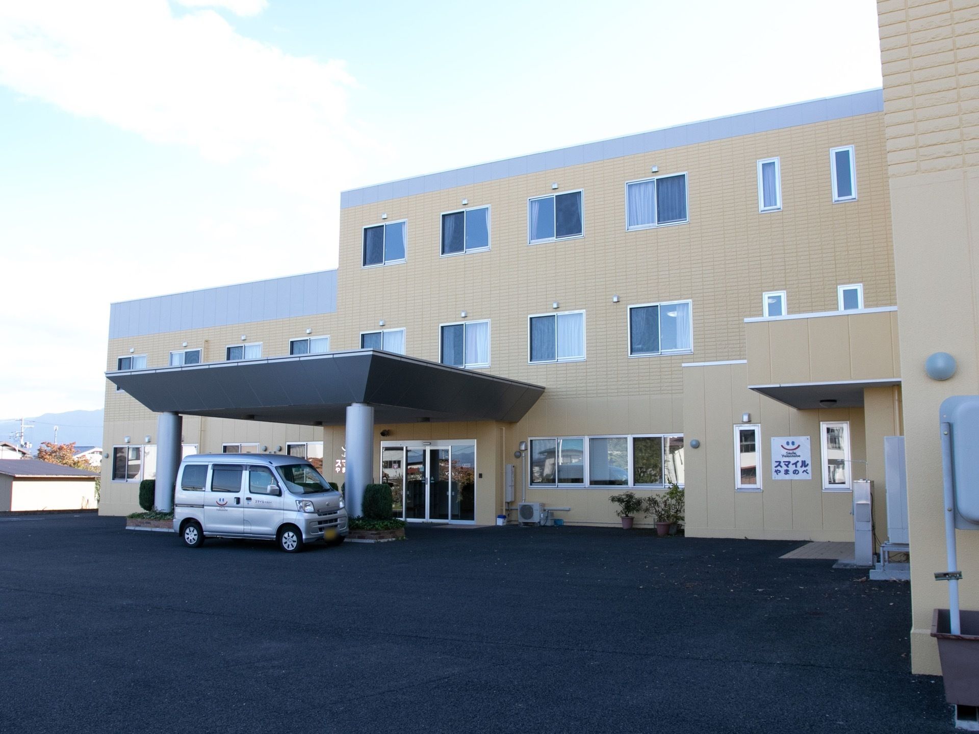 3階建ての建物で、玄関前には車寄せがある。玄関は自動ドアで、建物の周りはアスファルトで整備されている。