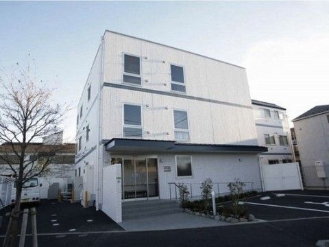駐車スペースが前方に設けられた3階建ての白い建物のエントランス