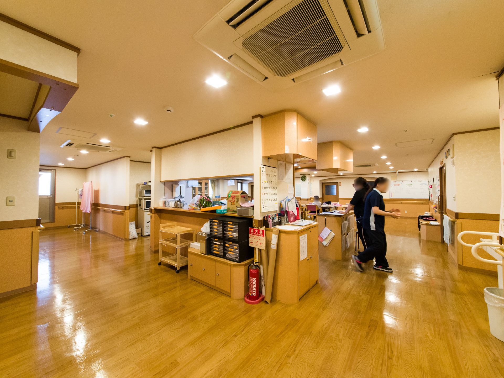 通路と食堂の間にはキッチンスペースが設けられ、施設内で3食の食事が調理されている。天井にはエアコンが設置され、壁には手すりが取り付けてある。