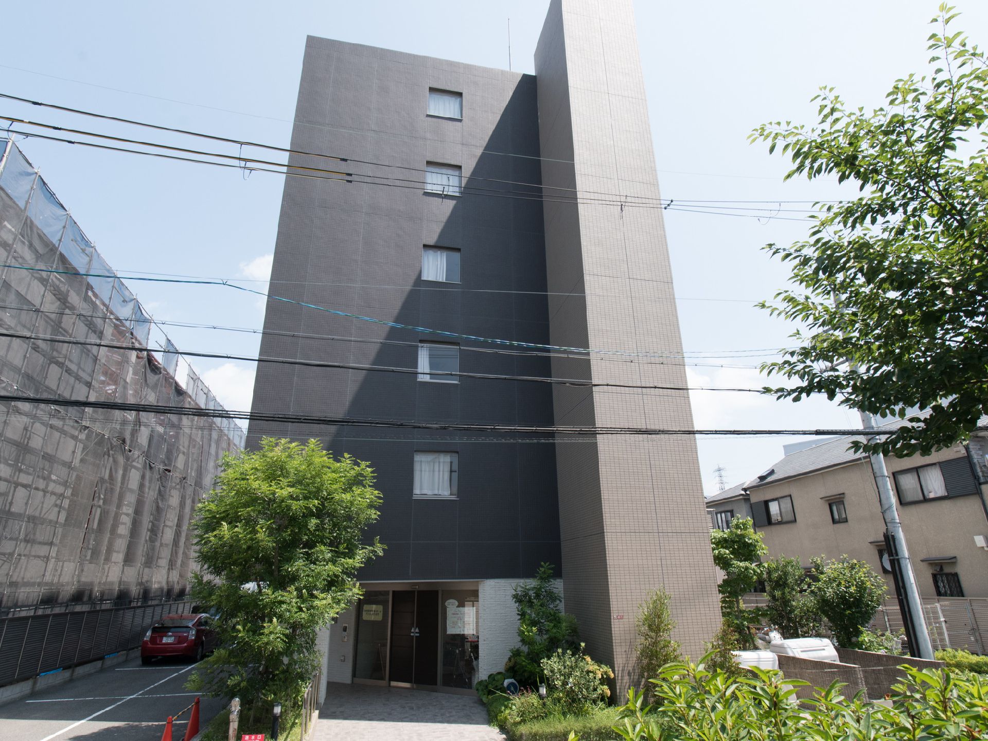 施設外観の様子。道路から1階の入口前には、様々な草木が植えられている。エントランスはガラス製の自動ドア。