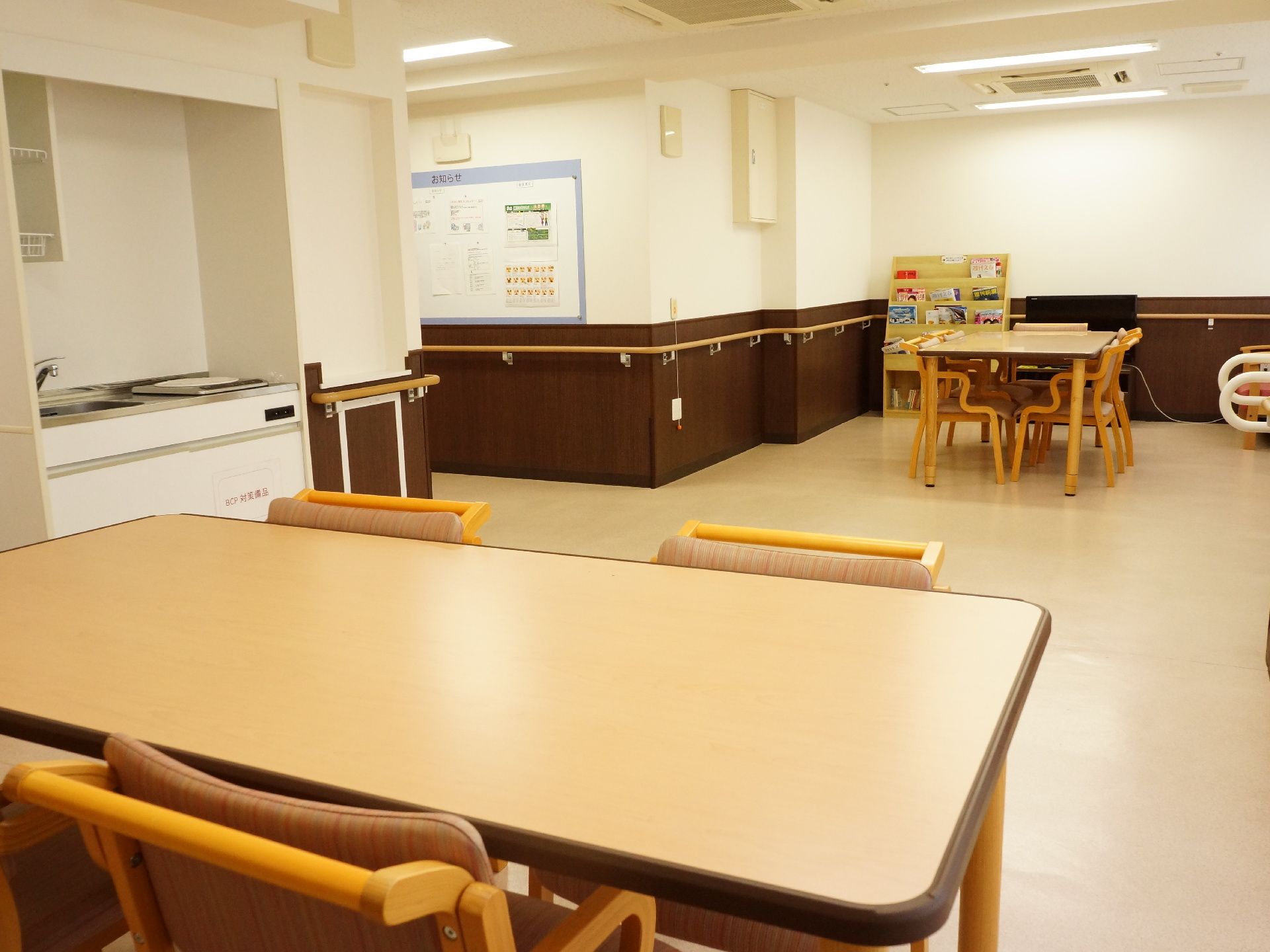 白とダークブラウンの落ち着きのあるフロア。テーブルセットがあり、壁には手すりが付いており、中央に簡易キッチンがある。